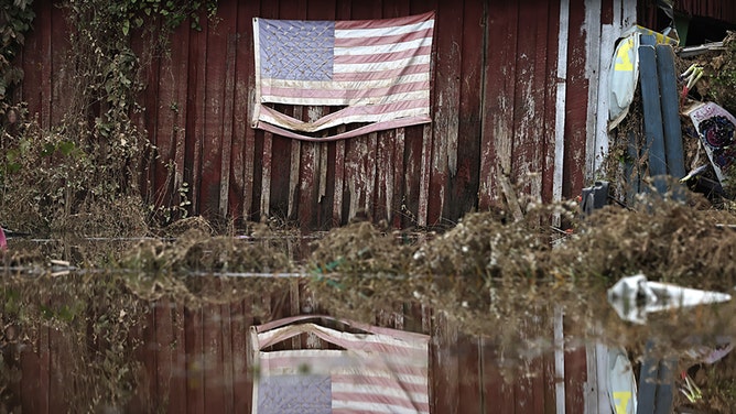 An American flag is reflected in floodwaters remaining from Hurricane Helene on October 4, 2024 in Swannan, North Carolina.